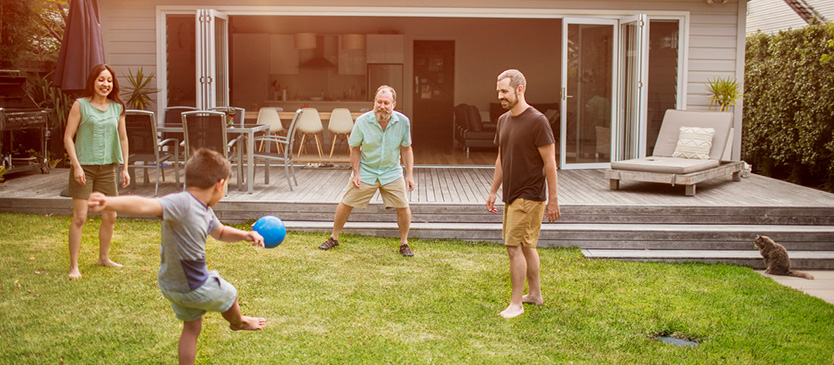 Family in backyard kicking soccer ball around 