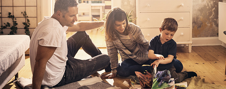 family sitting on the floor of their sons bedroom reading a pop up book